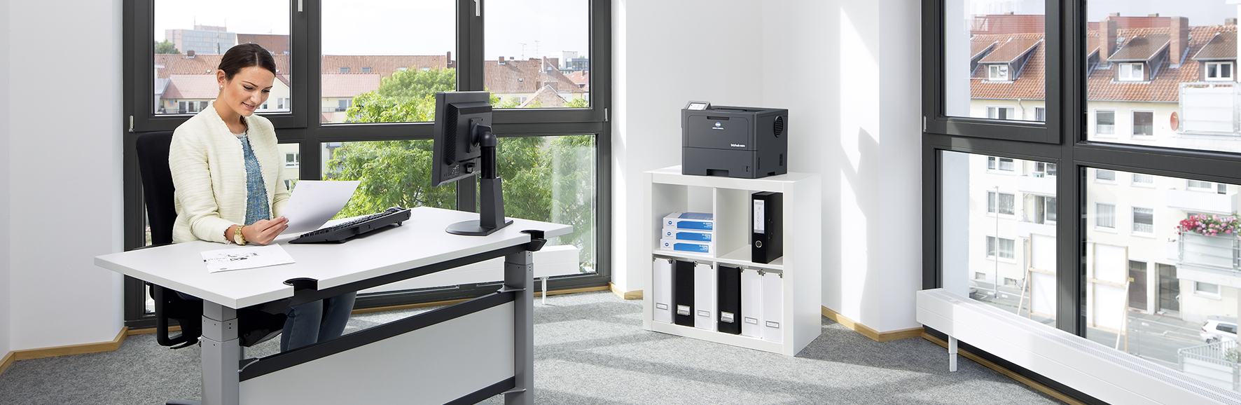 Frau sitzt an einem Schreibtisch im Eckbüro