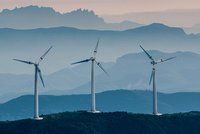Drei Windkrafträder vor hügeliger Landschaft