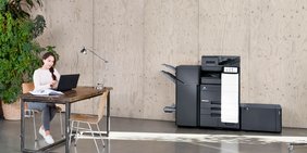 Konica Minolta MFP neben junger arbeitender Frau